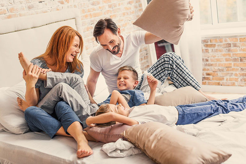 Glückliche Familie entspannt gemeinsam im Schlafzimmer eines Hauses